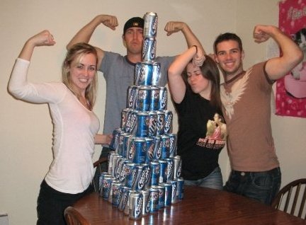 two men and two women with arms raised around a beer pyramid