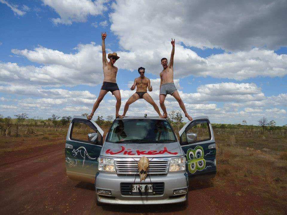 three guys standing on wicked van in underpants cheering in the outback