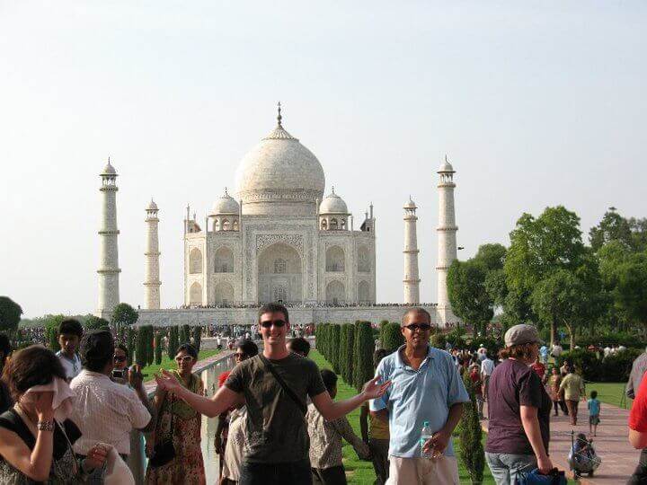 man in front of taj mahal with large group of people around