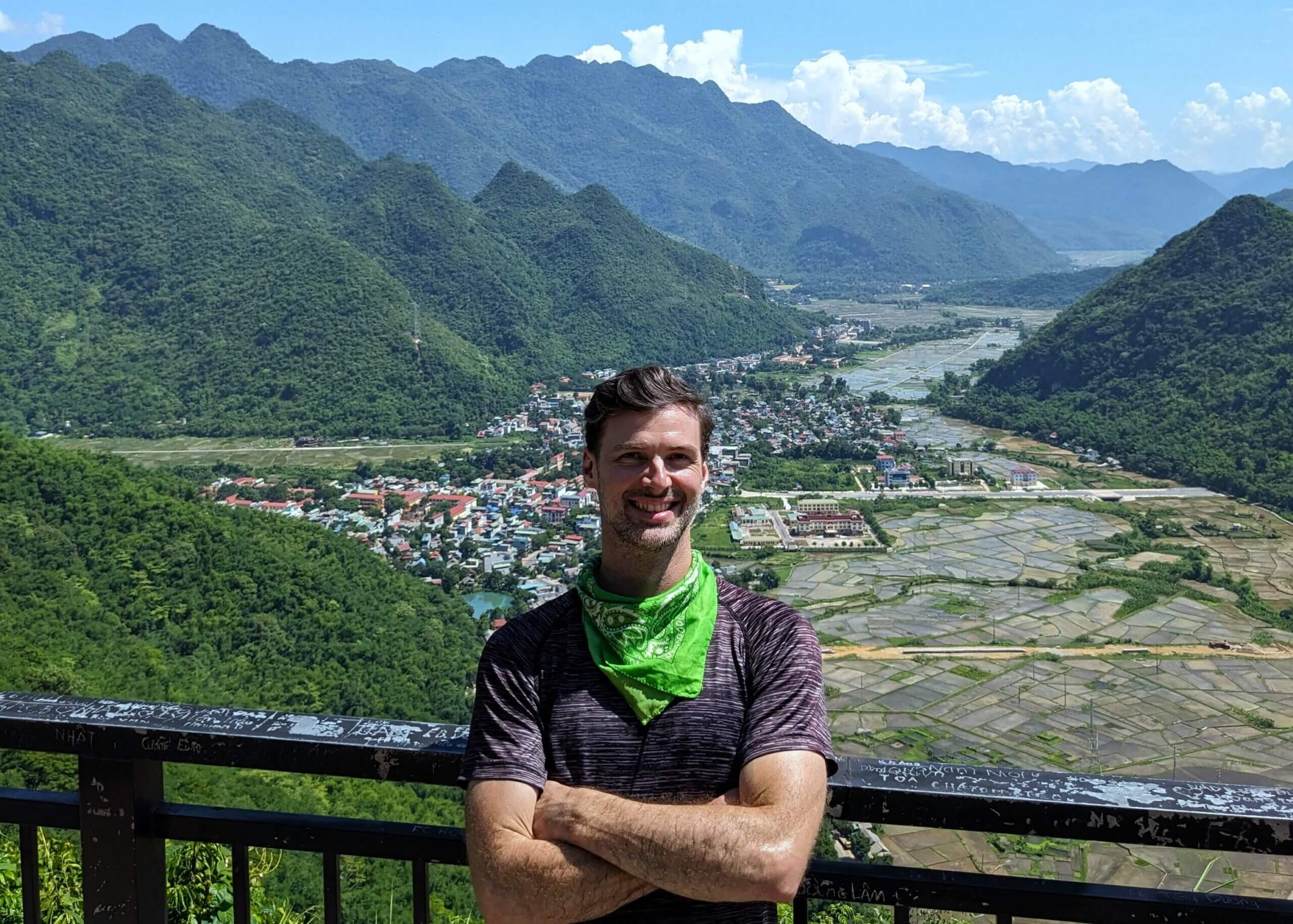 man standing arms crossed looking at camera with vietnam mountains in background